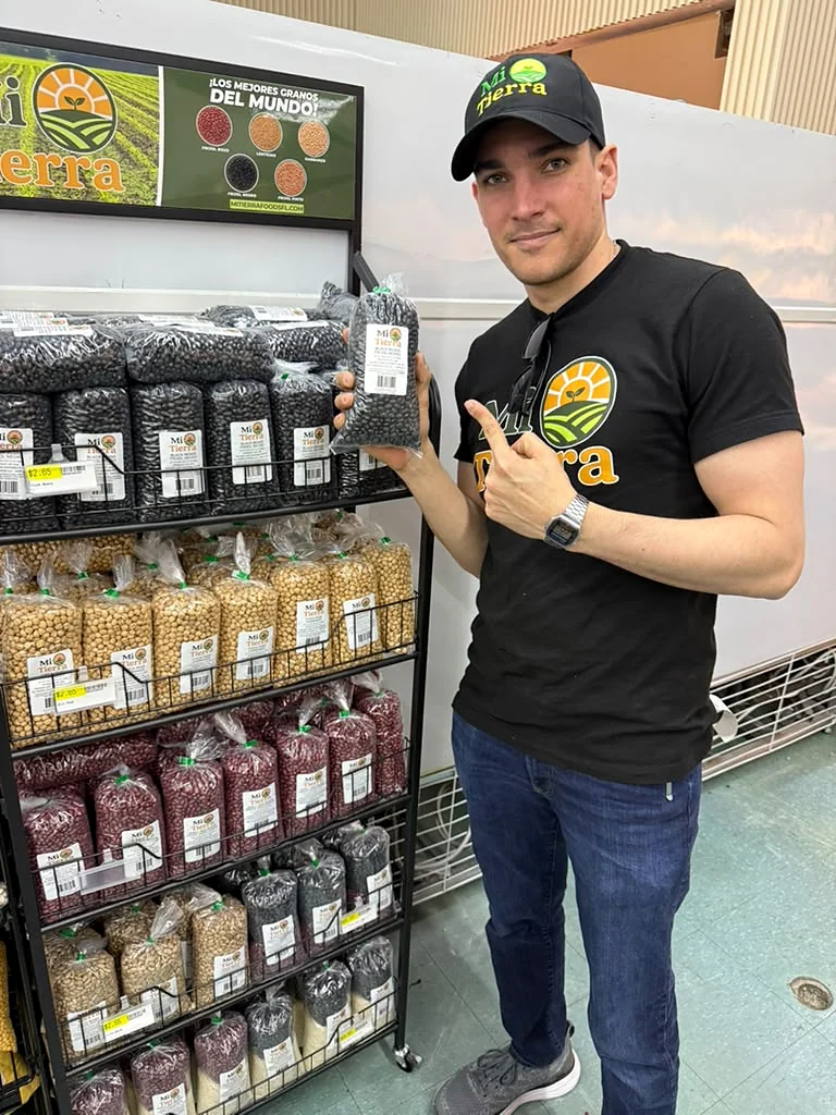 Equipo de Mi Tierra Foods mostrando una bolsa de frijol negro junto al exhibidor en tienda